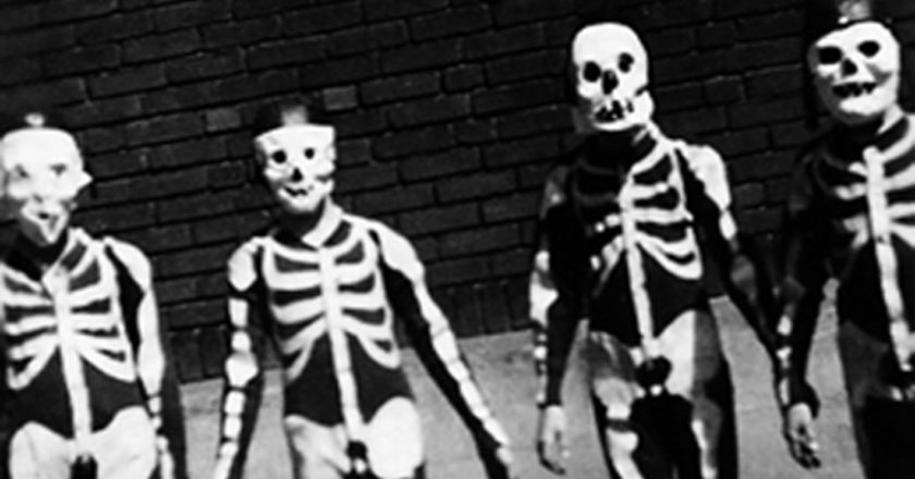 A black and white photo of four kids wearing vintage skeleton costumes