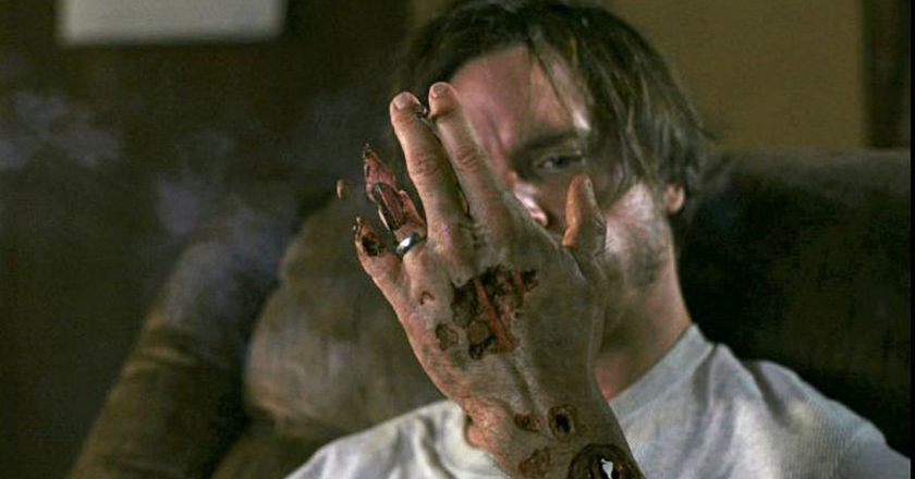 Lead character Bob, played by Aden Young looking at his hand as it starts to vanish.