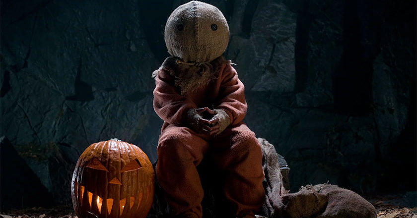 Sam from Trick 'r Treat sitting next to a jack-o'-lantern with his burlap sack