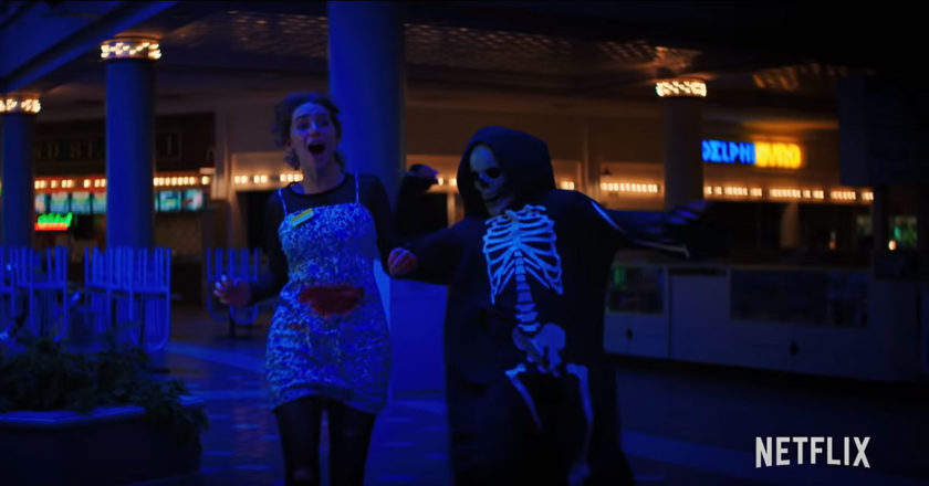 A person in a skeleton costume chases a girl with a knife in a mall in the trailer for "Fear Street: 1994"