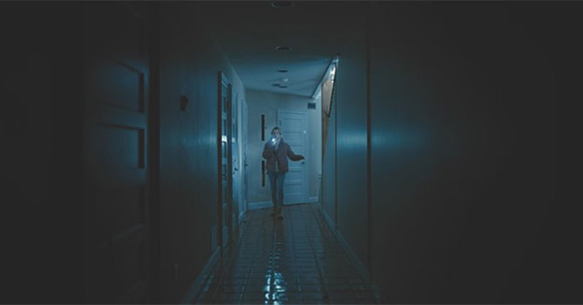 Actress Skyler Davenport navigates a dark hallway while holding up a cell phone in "See for Me"