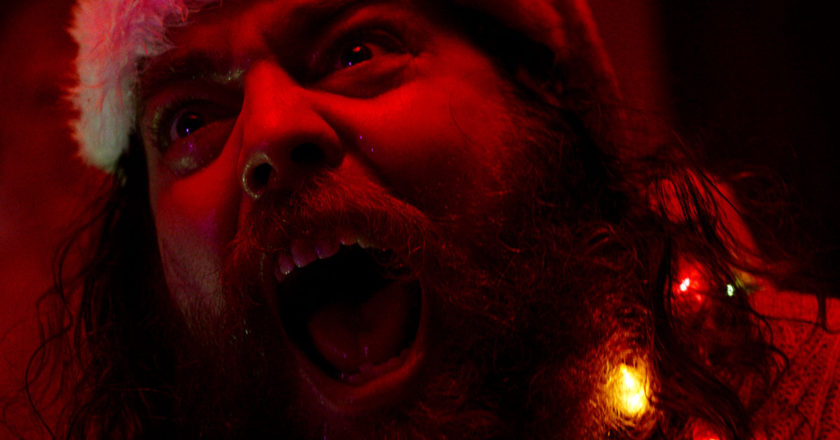 Jeremy Gardner screaming while wearing a Santa hat in "The Leech."