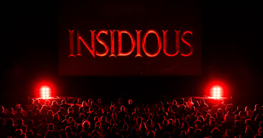 Movie screen with the insidious logo in front of a live audience