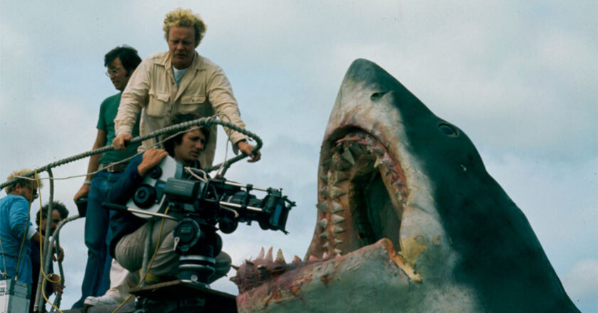 Director Steven Spielberg, kneeling with camera, during production of JAWS